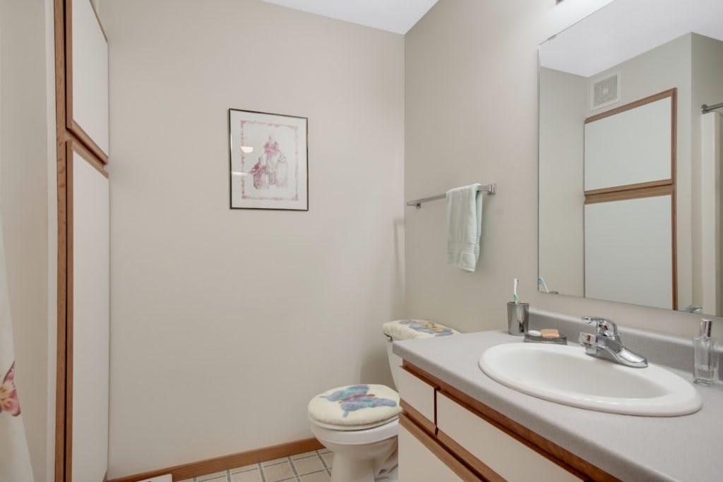 A tidy bathroom featuring a sink with a mirror above, a towel rack, and a toilet.