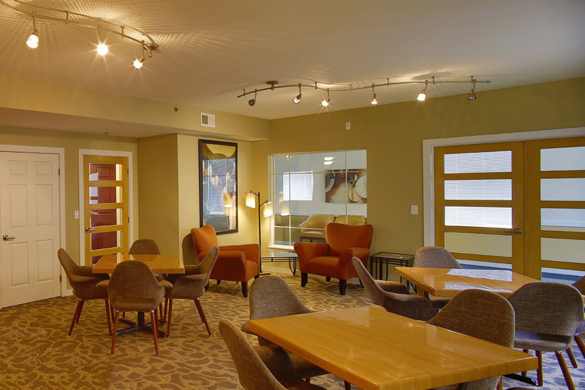 A modern lounge area with tables and chairs, featuring warm lighting and contemporary decor.