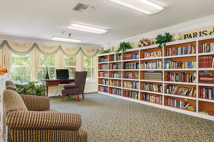 A cozy library corner with bookshelves, a computer desk, and comfortable seating.