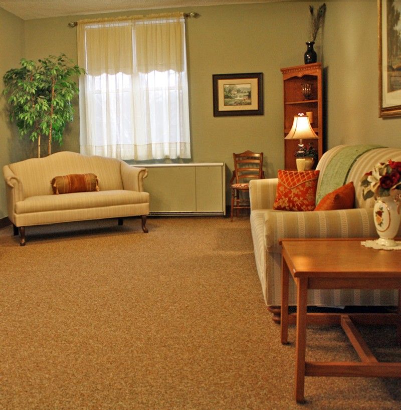 A cozy living room featuring sofas, a lamp, and wooden furniture with warm decor.