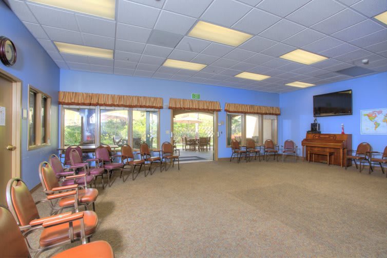 A spacious conference room with a circle of chairs, large windows, and ceiling lights.