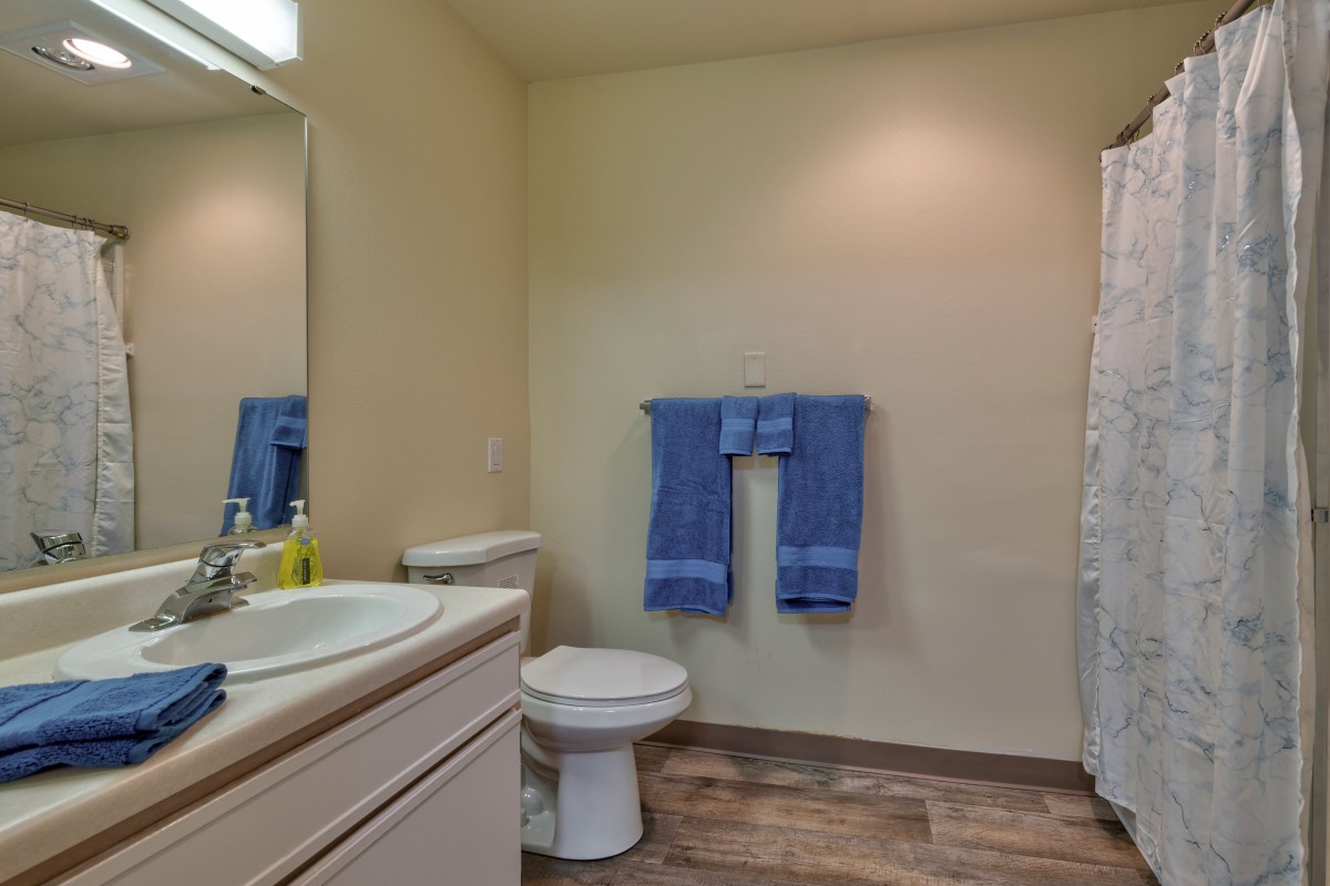 A clean and simple bathroom with blue towels, a sink, and a toilet.