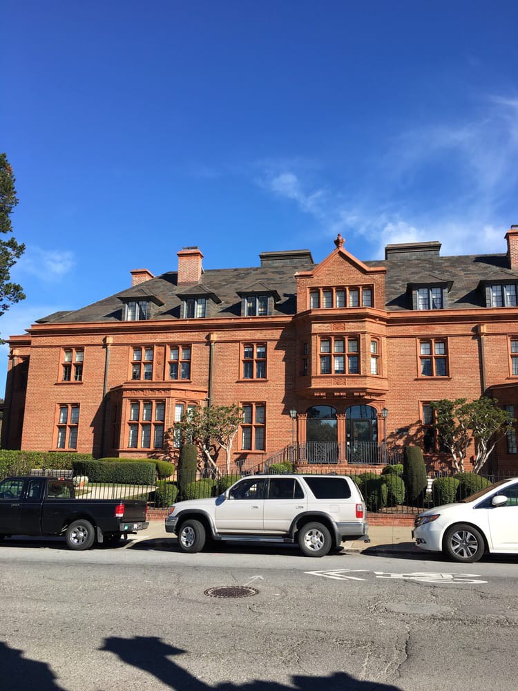 A historic brick building with parked cars in front on a sunny day.