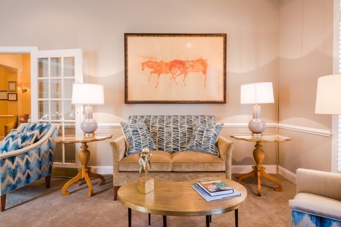 A cozy living room with a patterned sofa, flanked by side tables and lamps, and a large piece of artwork above.