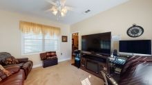 A cozy living room with a large television, sofa, and ceiling fan.