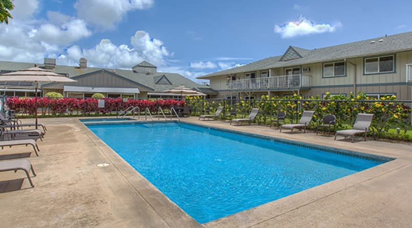A serene view of a swimming pool at a hotel resort on a sunny day.