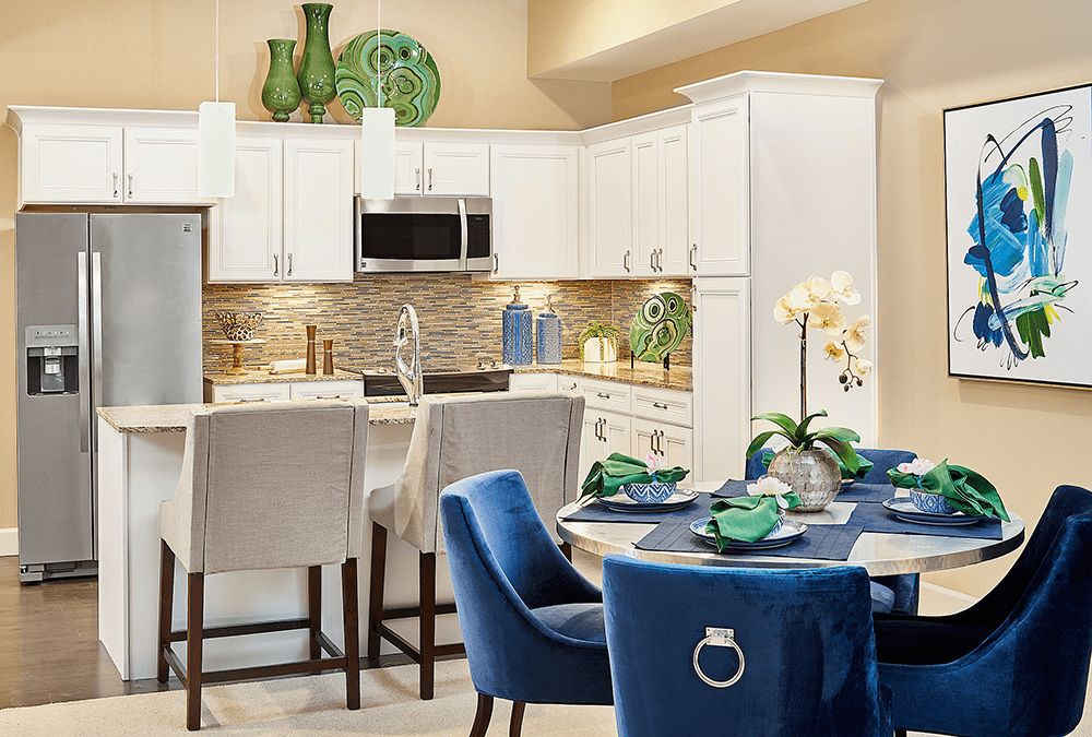A modern kitchen and dining area with white cabinets, blue chairs, and decorative elements.