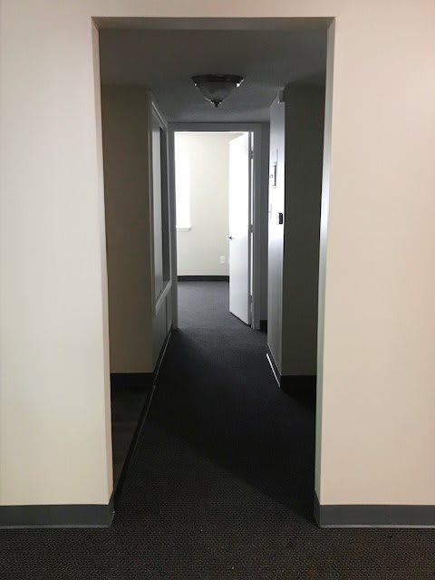 A quiet hallway with multiple doors and carpeted flooring.