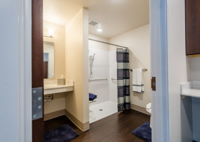 A modern bathroom featuring a shower, sink, and mirror with neatly arranged towels.