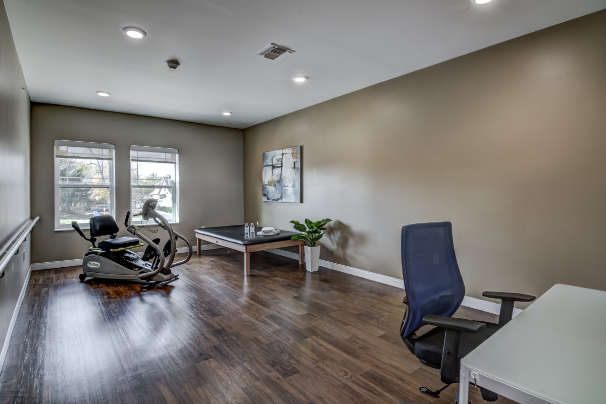 A modern office space featuring a desk, chair, and exercise equipment on a wooden floor.