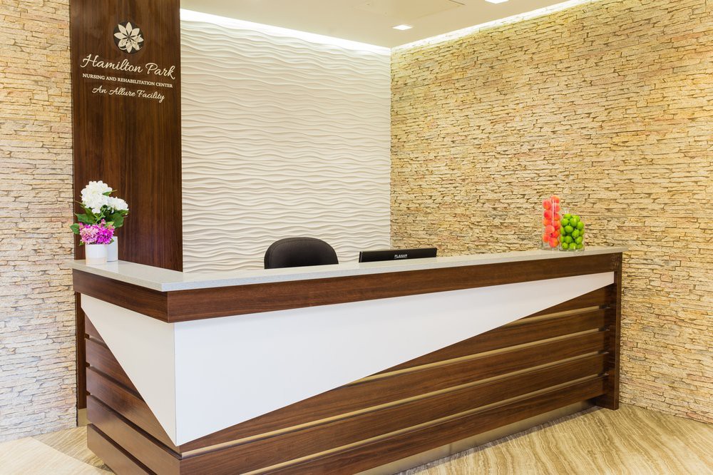 A modern office reception area featuring a wooden desk and stylish lighting.