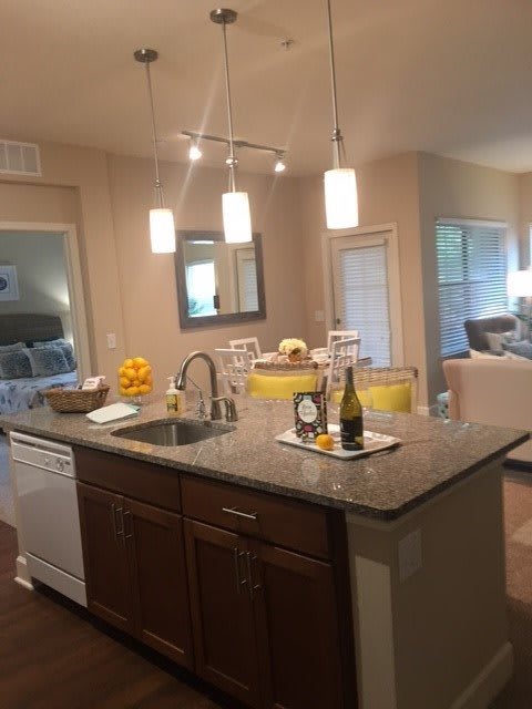 A modern kitchen with an island, featuring pendant lighting and an open floor plan.