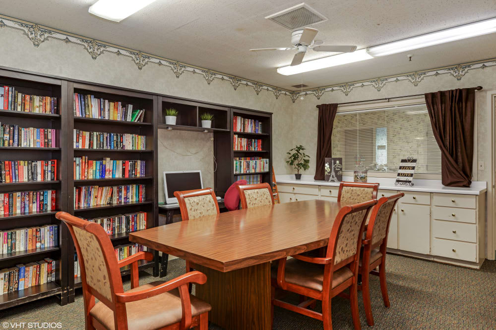 A cozy conference room with a large table, surrounded by bookshelves filled with books.