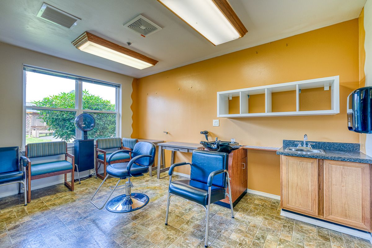 An empty hair salon with chairs, sinks, and bright lighting.