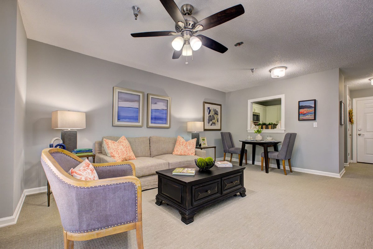 A cozy living room with neutral tones, featuring a comfortable sofa, coffee table, and decorated with artwork.