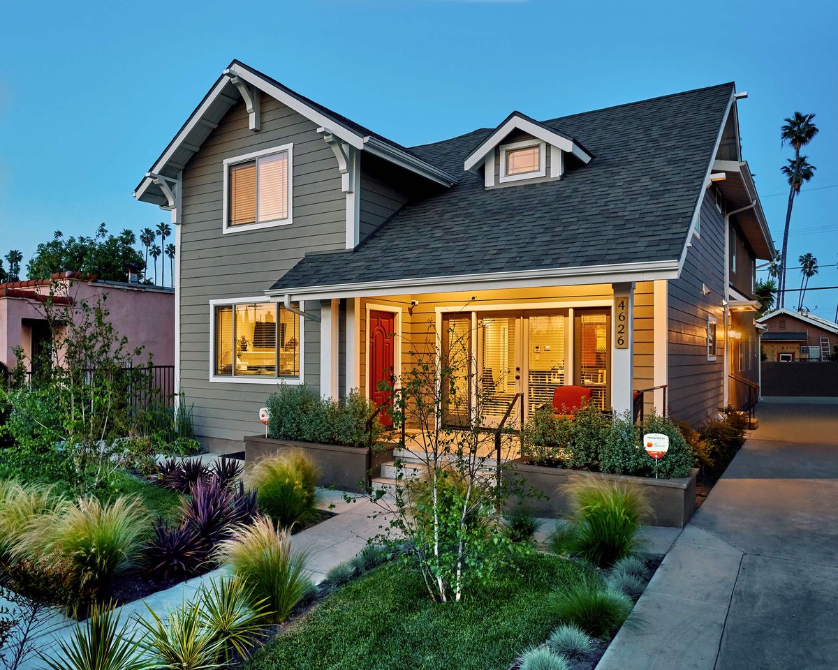 A beautifully lit residential house with a well-maintained garden during the evening.
