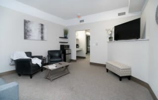 A modern living room with minimalist decor, featuring comfortable seating and a wall-mounted television.