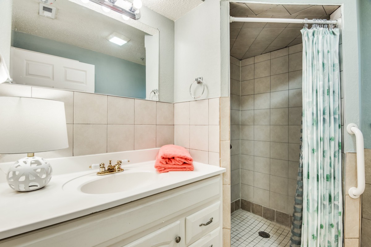 A clean and modern bathroom with a sink, mirror, and shower.