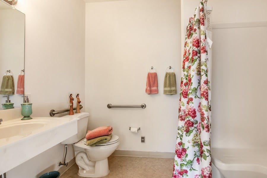 A bathroom featuring a floral shower curtain and neatly arranged towels.