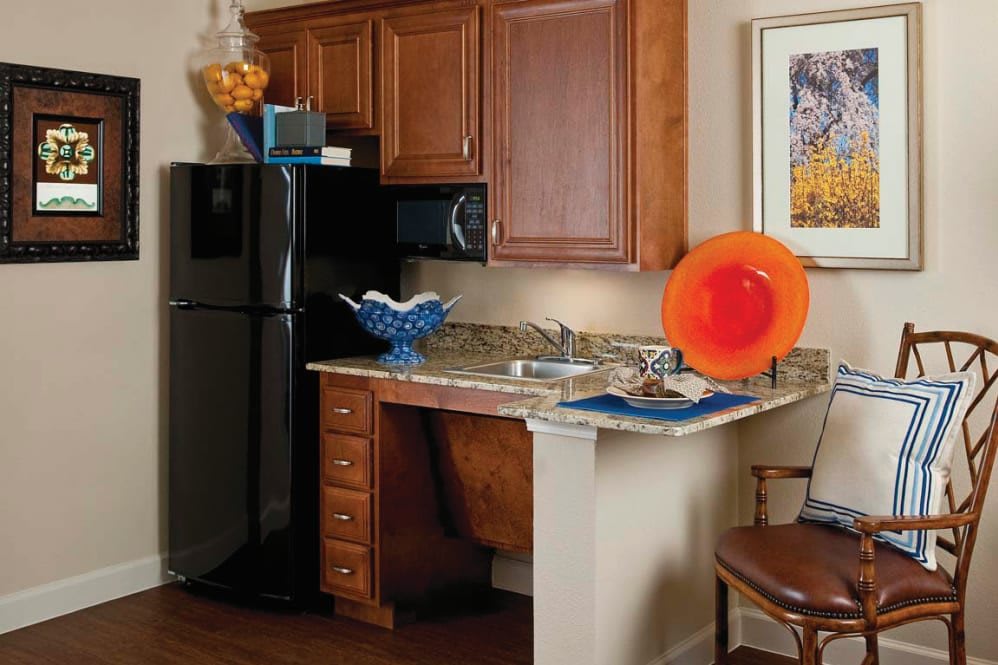 A cozy kitchen area with wooden cabinets, a granite countertop, and colorful decorative items.