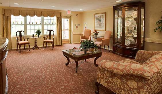 A cozy, traditionally styled living room with elegant furniture and carpeted flooring.