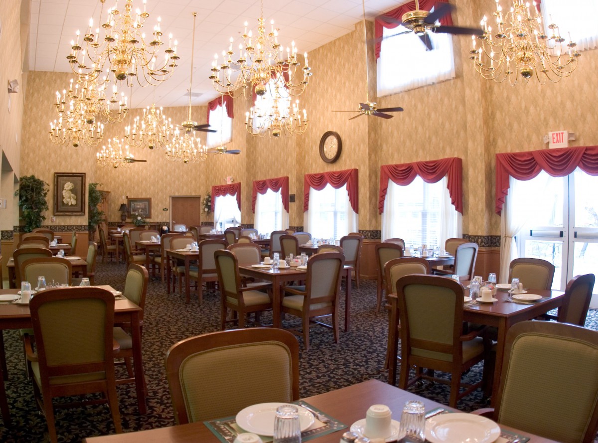 An elegant dining room with chandeliers, arranged tables, and large windows.
