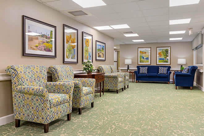 A spacious waiting room featuring comfortable seating, decorative artwork, and carpeted flooring.