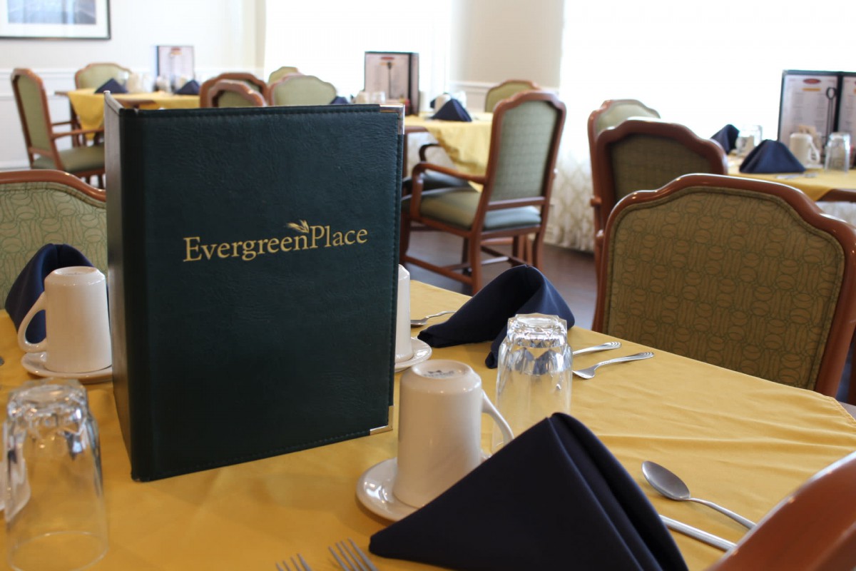 A sophisticated dining setup at Evergreen Place, featuring a neatly arranged table with a menu and napkins.