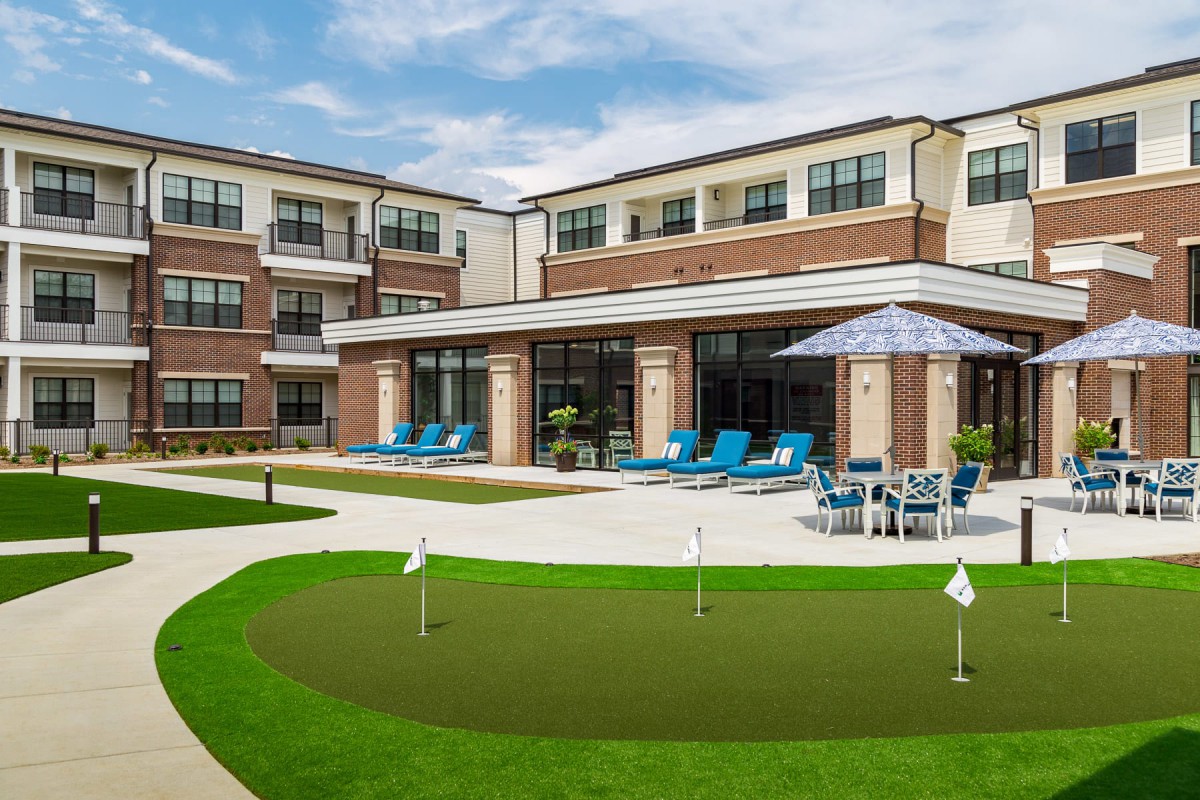 A modern apartment complex with outdoor amenities including a swimming pool and putting green.