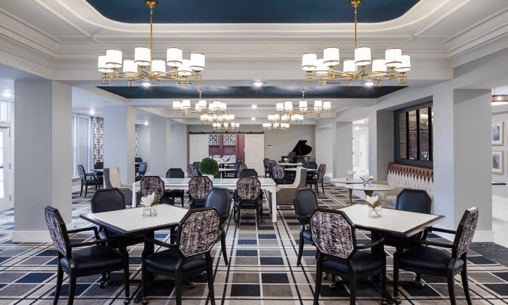 A sophisticated dining area with elegant chandeliers and a grand piano, featuring modern furnishings and stylish decor.