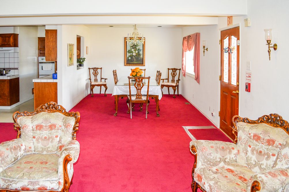 A traditional living and dining space with red carpeting and antique furniture.