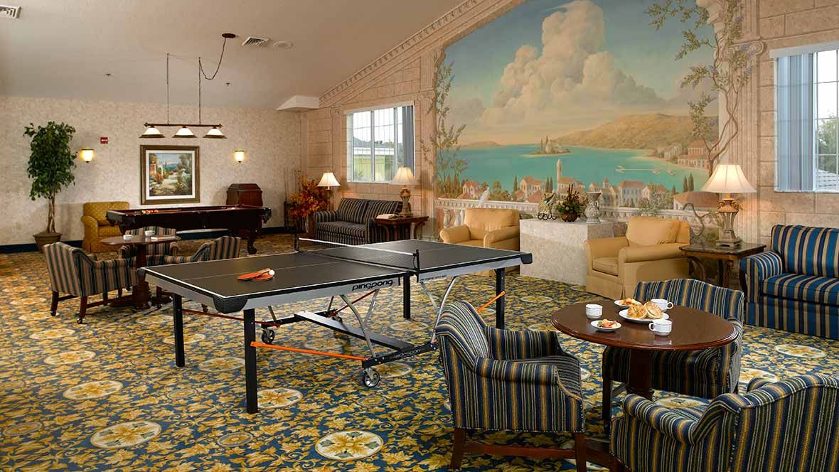 A cozy game room featuring a ping pong table, billiards, and a seating area with a large mural on the wall.