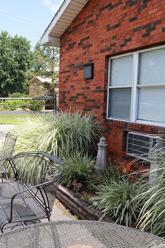 A cozy outdoor seating area with plants and a brick wall backdrop.