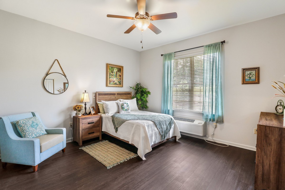 A modern bedroom with a bed, nightstand, and natural lighting from a window.