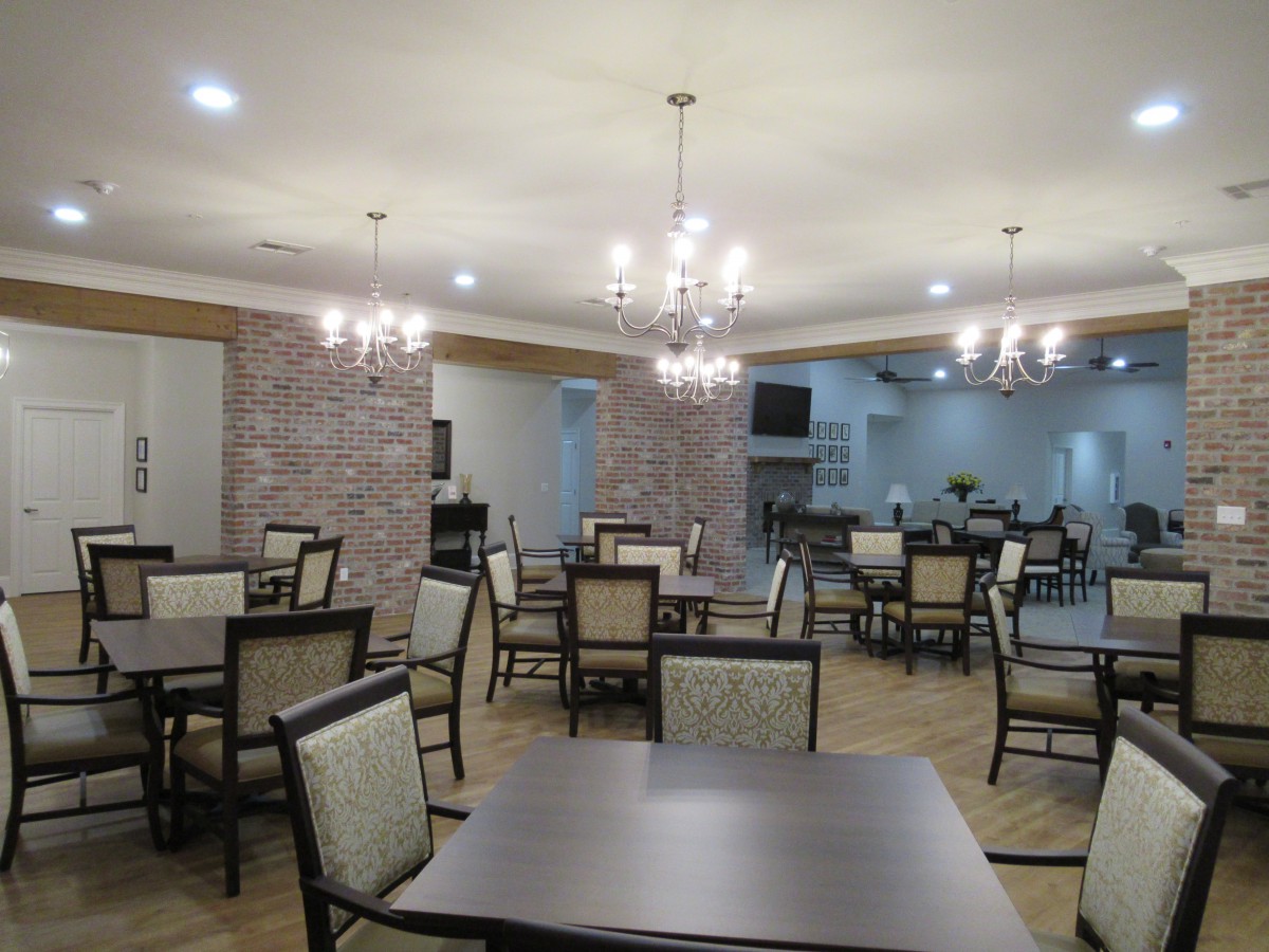 An empty dining area with neatly arranged tables, chairs, and decorative chandeliers.