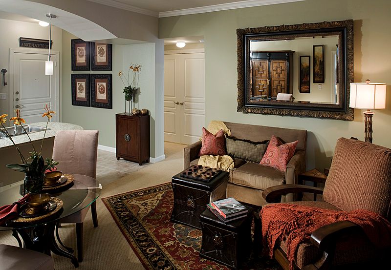 A cozy living room featuring a sofa, decorative pillows, a large mirror, and various artworks on the walls.