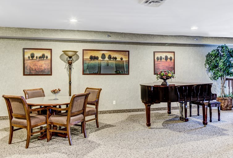 A cozy room with a grand piano, artwork on the walls, and comfortable seating.