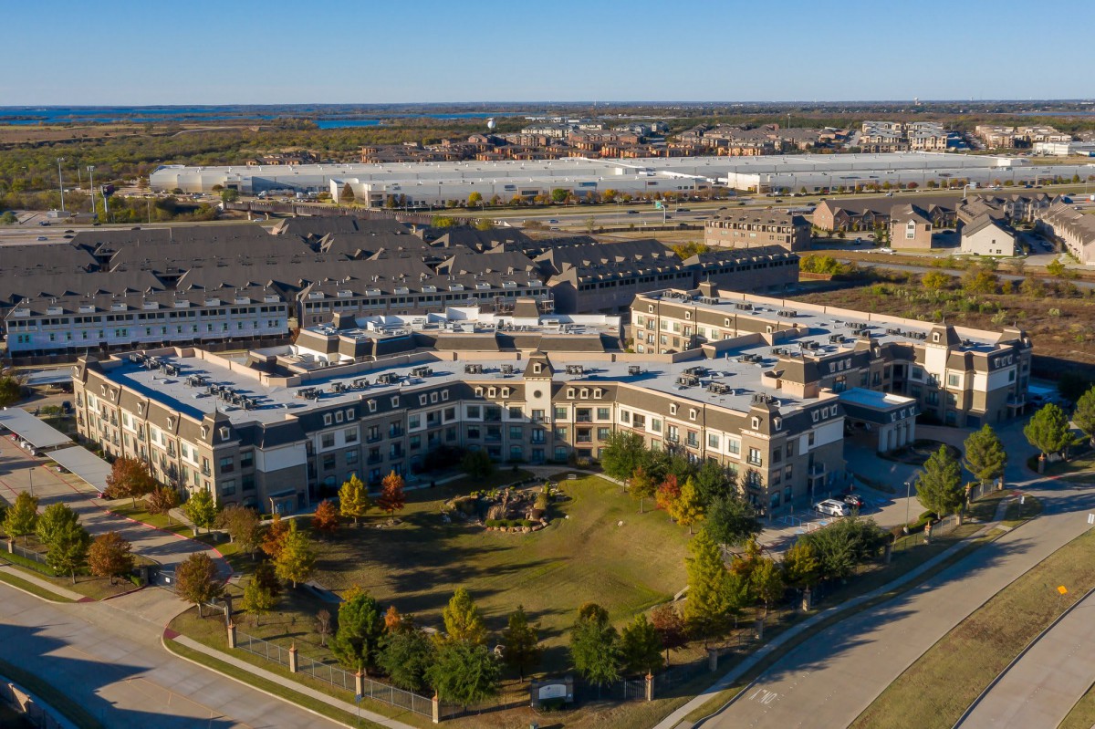 Aerial view of a residential complex with surrounding green spaces and a suburban landscape.