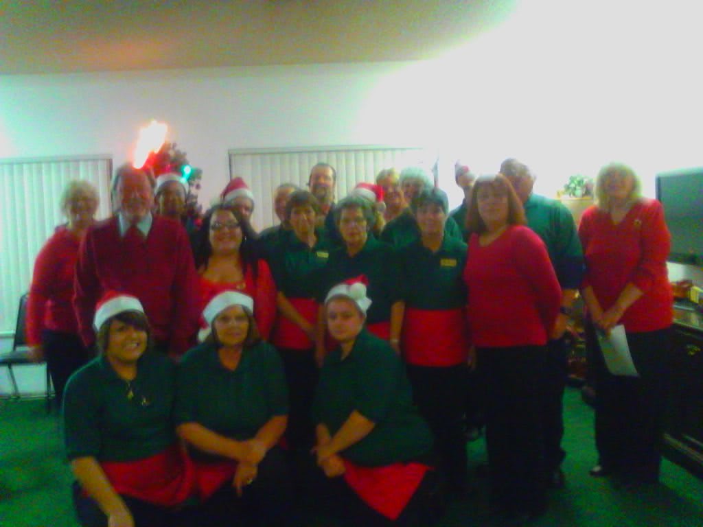 A group of people wearing Santa hats and festive clothing, posing for a holiday-themed photo.