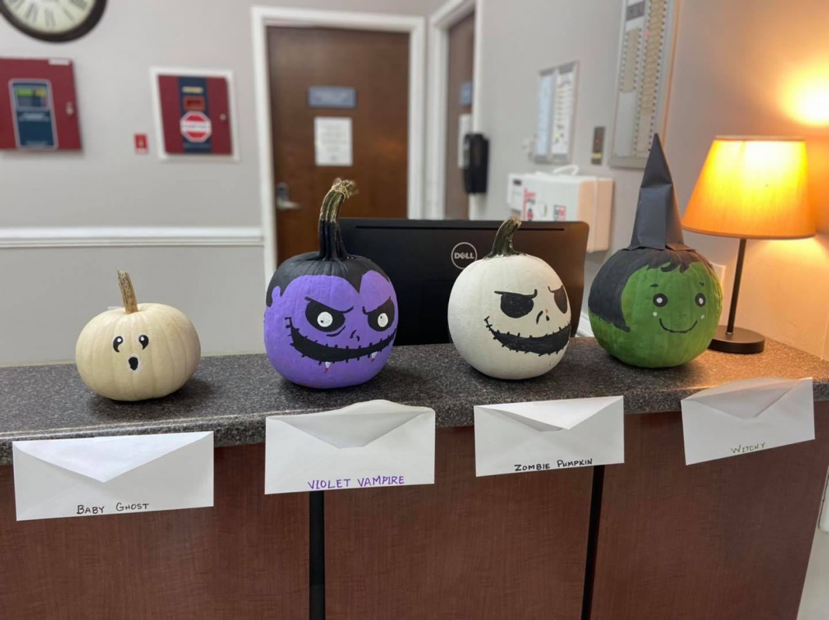 A row of creatively painted pumpkins on display in an office for Halloween.