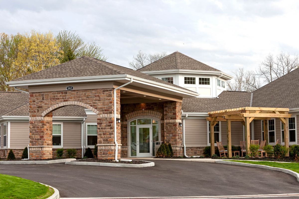 A modern building with stone and siding exterior, featuring a covered entrance.