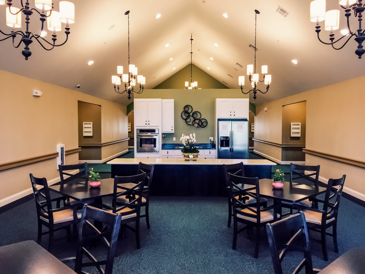 A modern dining area with a central kitchen and stylish chandeliers.
