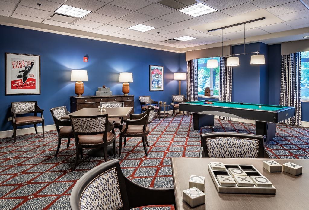 A cozy recreation room featuring a pool table and several small game tables for leisure activities.