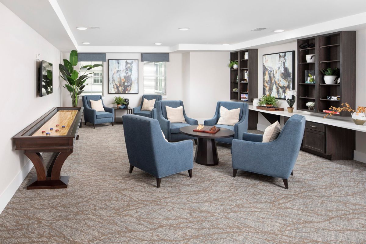 A modern lounge area with blue upholstered chairs and a central table, featuring stylish decor and artwork on the walls.