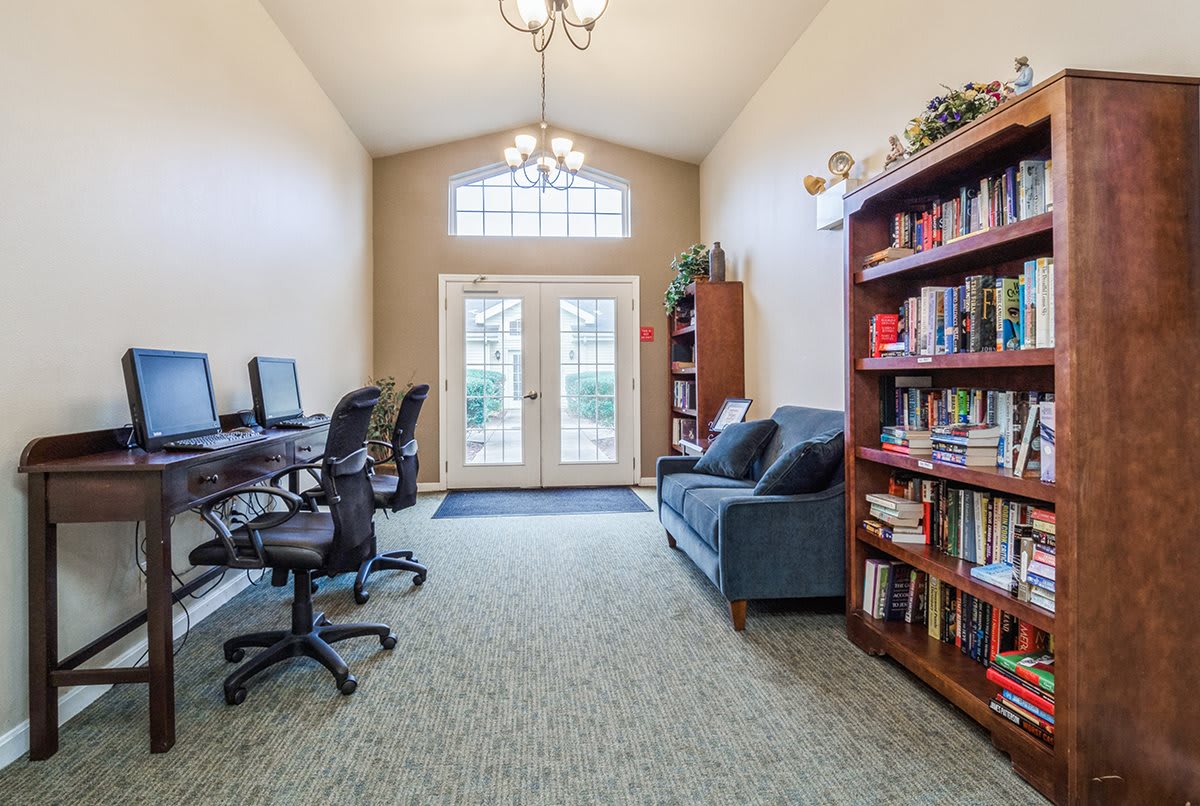 A cozy reading room with computers, a sofa, and a bookshelf full of books.