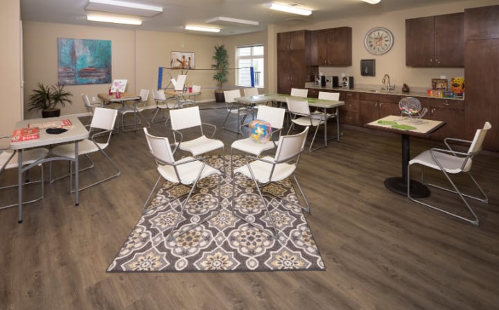 A modern conference room with white chairs arranged around tables on a patterned carpet.