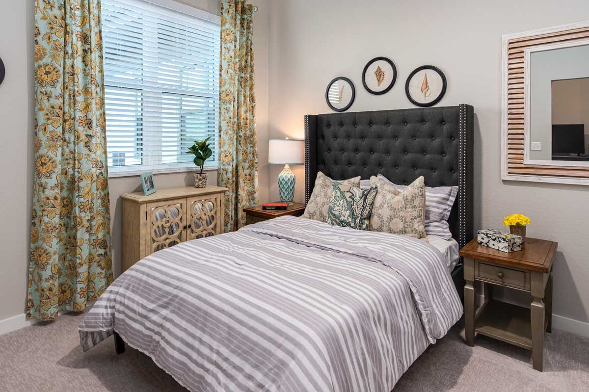A well-decorated bedroom with a neatly made bed, cushioned headboard, and stylish accents.