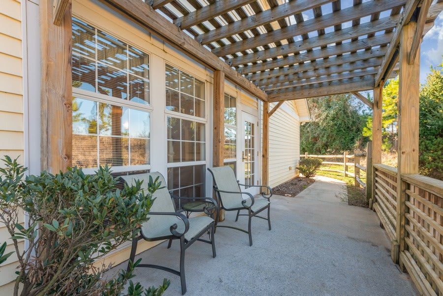 A cozy outdoor patio with chairs under a pergola.