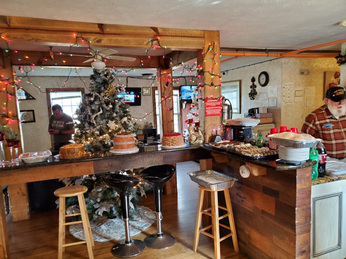 A cozy cafe interior decorated for the holidays with a Christmas tree and festive ornaments.