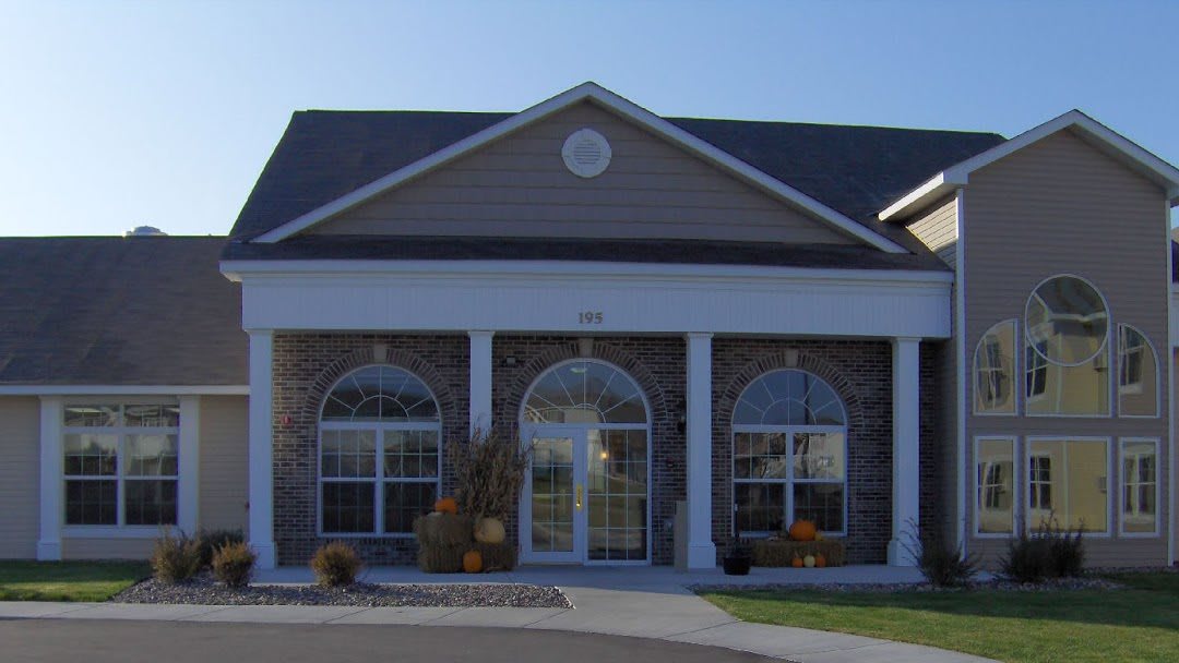 Front view of a residential building with large windows and an arched entrance.